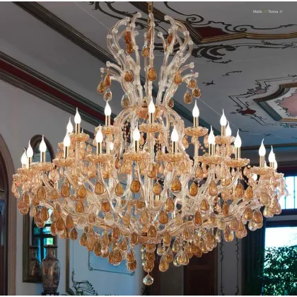 Zdjęcie Żyrandol Mariateresa z pozłacaną metalową ramą pokrytą przezroczystymi szklanymi ramionami z elementami ozdobnymi i zawieszkami w kolorze bursztynowym - Il Paralume Marina