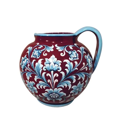 Picture Italian ceramic jug with decoration with scrolls and flowers on shiny dark red glaze